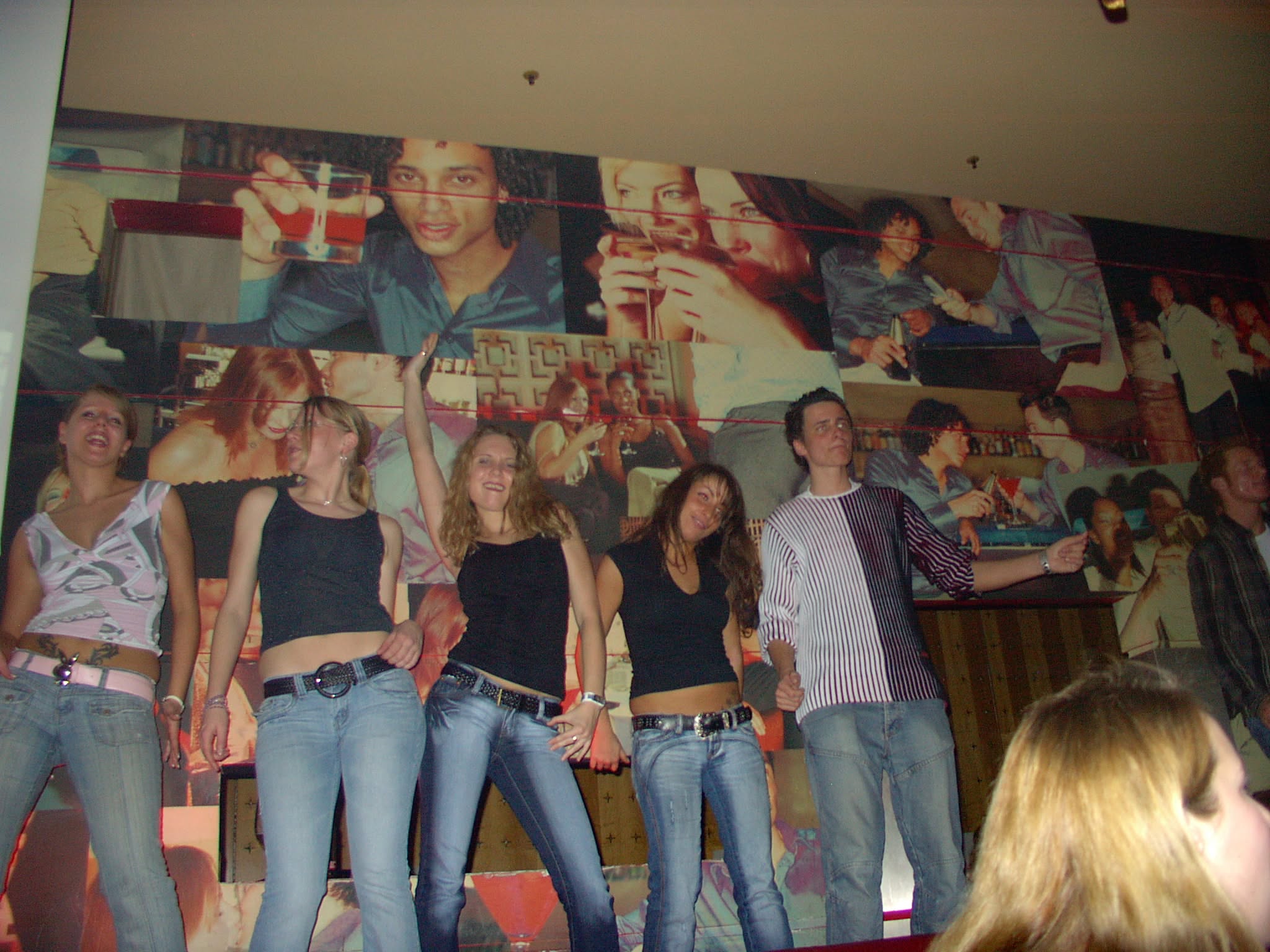 Mehrere Gäste feiern vor einer Wand mit Fotomotiven.