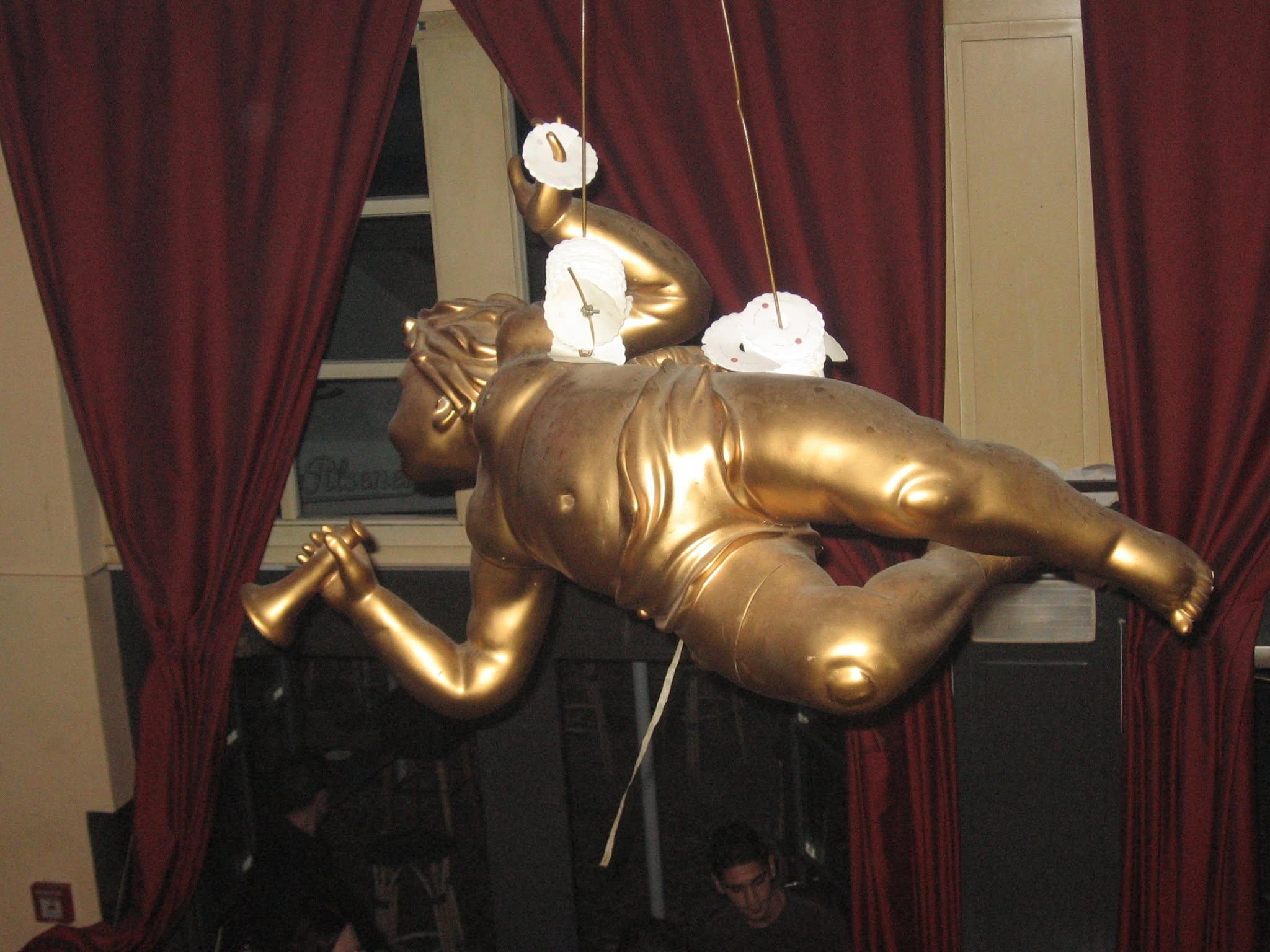 Goldfarbene dekorative Figur vor roten Vorhängen.