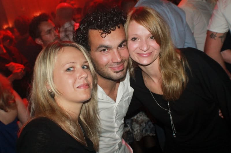 Drei Gäste posieren gemeinsam im Partylicht.
