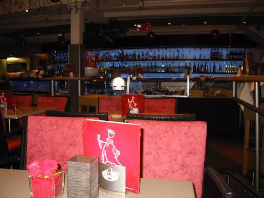 Rote Sitzbänke mit KÖNIG-Motiv vor der beleuchteten Bar.